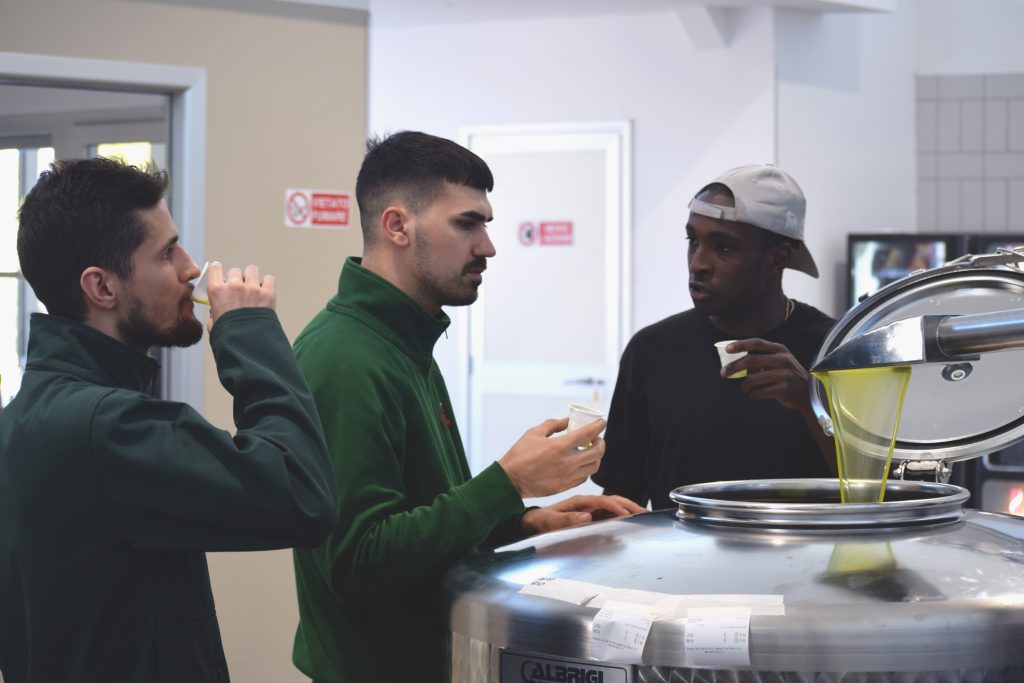 Denis Okore, Giuseppe Sacco und Team bei der Herstellung von apulischem Bio-Olivenöl in Italien.